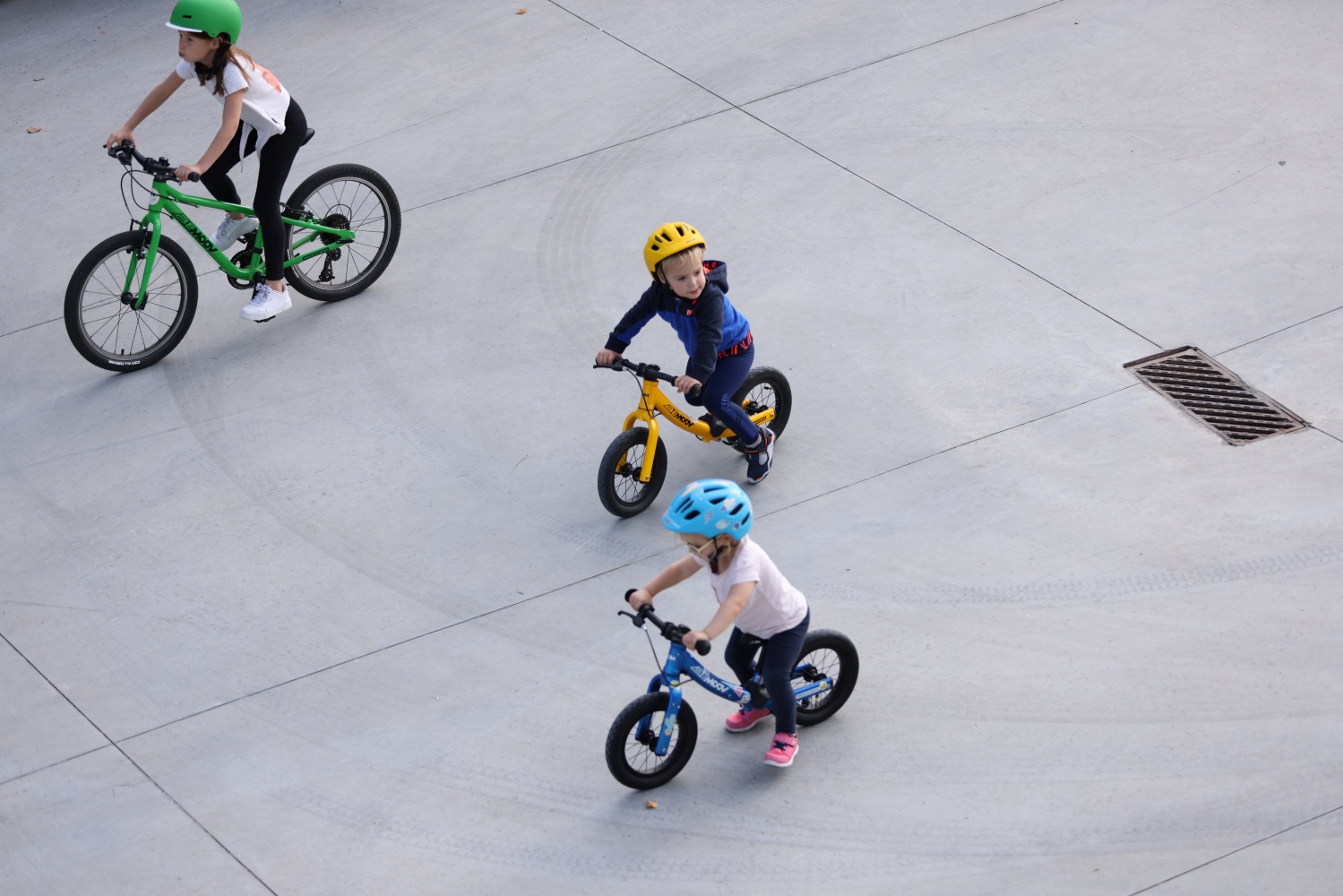 Trys vaikai važiuojantys dviračiais