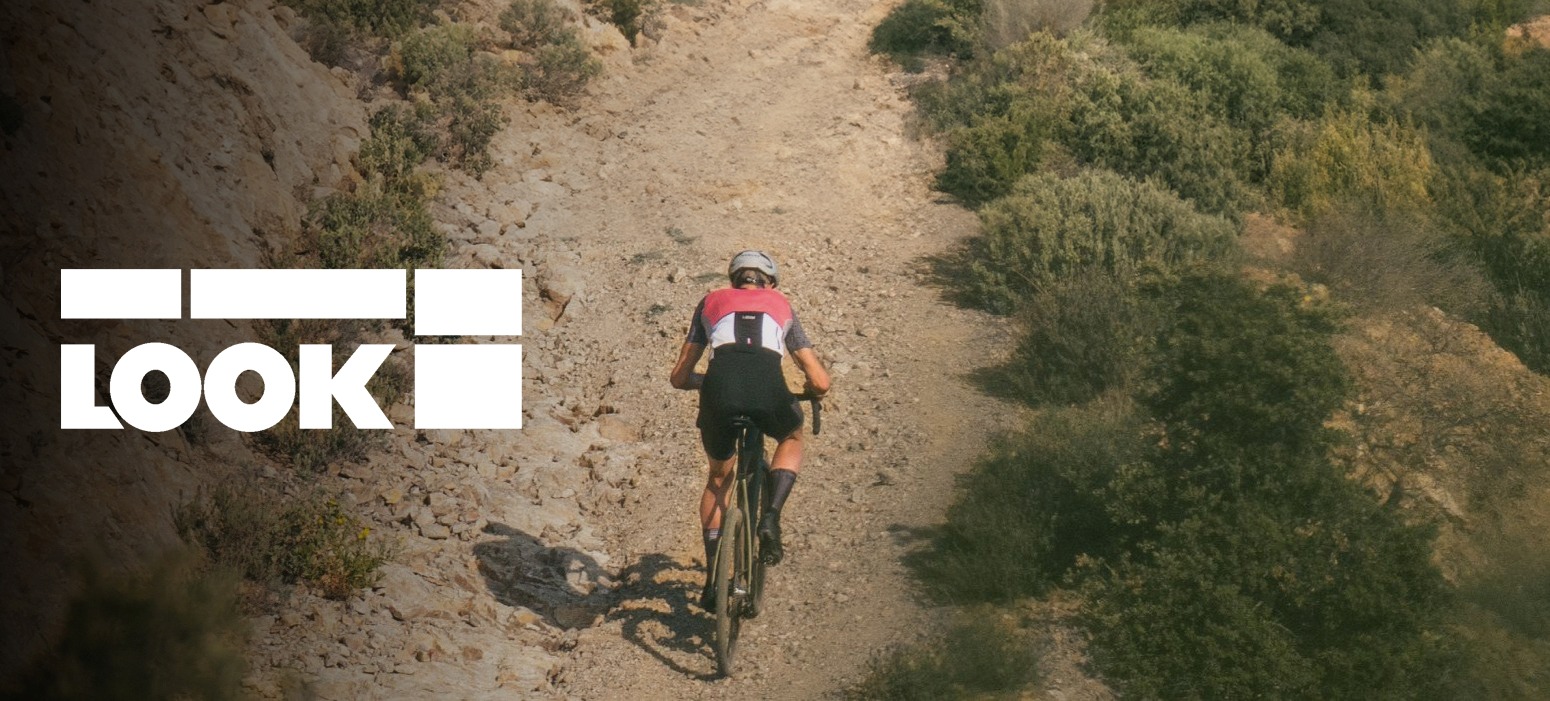 Mergina važiuojanti dvyračiu į kalną žvyrkeliu