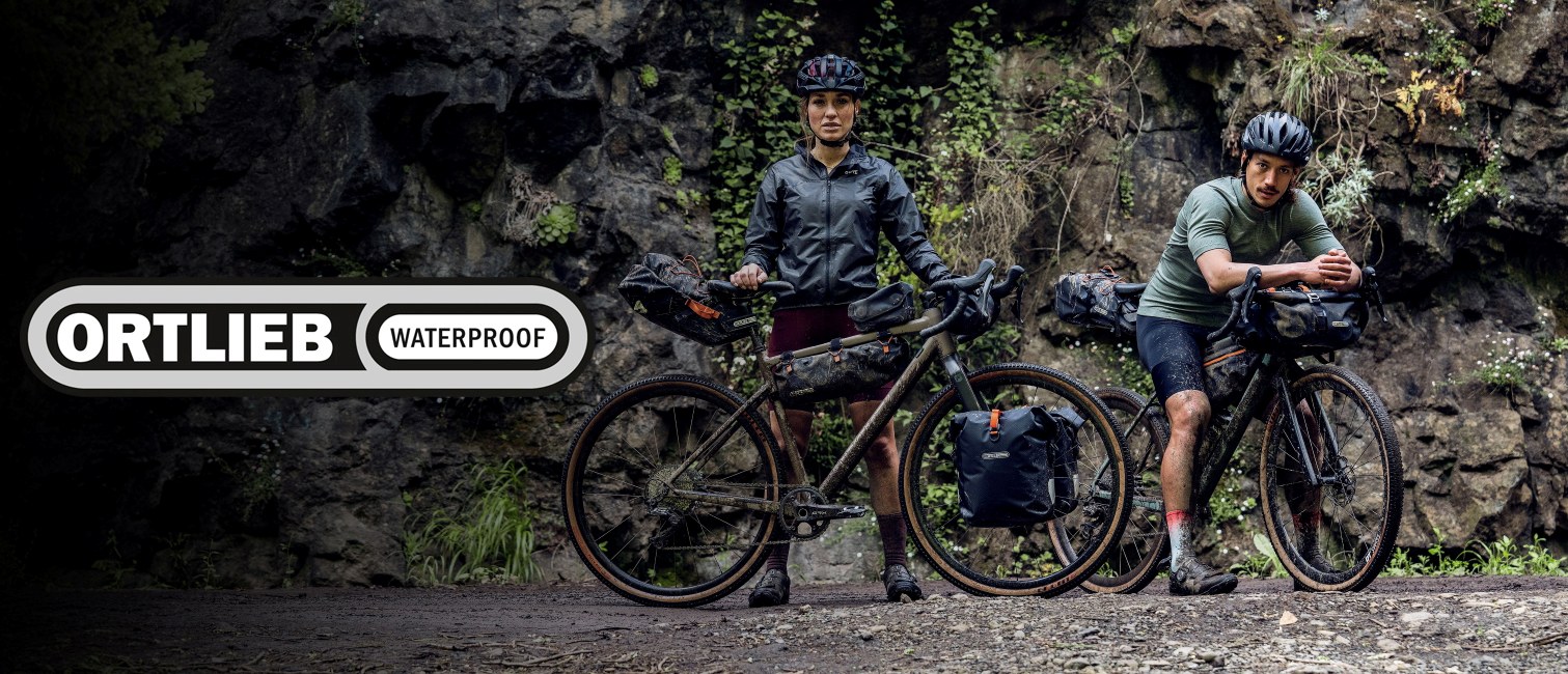 Woman and man holding bicycles loaded with bikepacking bags