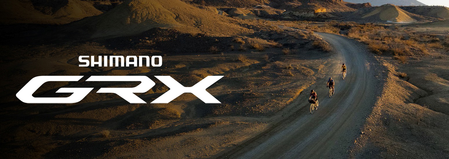 Trys dviratininkai važiuojantys žvyrkeliu