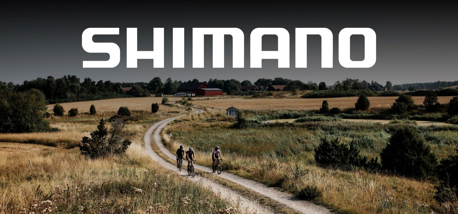 Trys dviratininkai važiuojantys žvyrkeliu